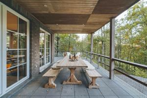 a patio with a wooden table and benches on a porch at Le Brocard in Durbuy
