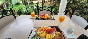 a table with two trays of fruit and orange juice at Prince Villa Sigiriya in Sigiriya