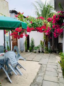 patio ze stołem, krzesłami i kwiatami w obiekcie Jerrys Dive Lodge Rasdhoo w mieście Rasdhoo