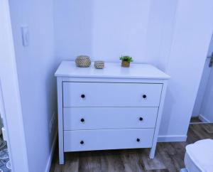 a white dresser with two plants on top of it at Logement proche Hypercentre CAEN in Caen