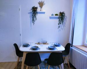 a white table with chairs and blue dishes on it at Logement proche Hypercentre CAEN in Caen