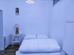 a white bedroom with a white bed and a table at Logement proche Hypercentre CAEN in Caen