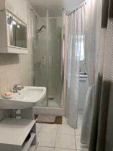 ein weißes Bad mit einer Dusche und einem Waschbecken in der Unterkunft La Costonnerie in Leigné-sur-Usseau