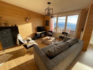a living room with a couch and a large window at LA PERLE DES CAILLOUX EXCEPTIONNEL et COSY in Font Romeu Odeillo Via