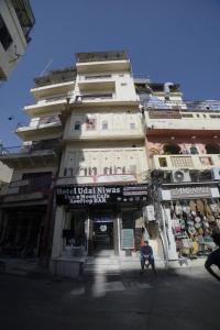 a tall building with a man sitting in front of it at Hotel Udai Niwas By The Lake in Udaipur