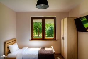 sypialnia z łóżkiem i oknem w obiekcie Zarębisko - noclegi całoroczne w Zwierzyńcu