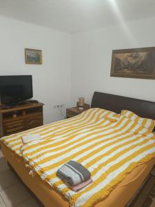 uma cama com um cobertor listrado e uma televisão em Vila Jovana B em Rogljevo
