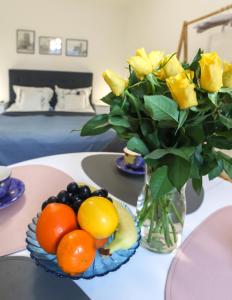 un jarrón de rosas amarillas y fruta sobre una mesa en Apartament Żeromskiego 1, en Sandomierz