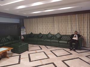 Ein Mann auf einer Couch im Wohnzimmer in der Unterkunft Hotel Benzz Park Chennai in Chennai