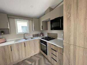 a kitchen with wooden cabinets and a stove top oven at 2021 2 bedroom static caravan in 5 stars Patrington haven holiday park in Patrington