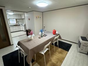 a room with a table with chairs and a kitchen at 名寄ベース in Nayoro