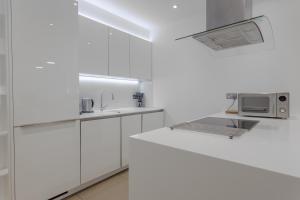 a white kitchen with a sink and a microwave at Beautiful 2-Bed Apartment in Central London in London