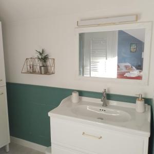 La salle de bains est pourvue d'un lavabo blanc et d'un miroir. dans l'établissement Ô 87 - chambres d'hôtes, à Amboise