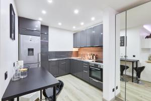 cocina con armarios grises y mesa negra en Appartement Loft Cosy - 15mn de Paris !, en Fontenay-aux-Roses