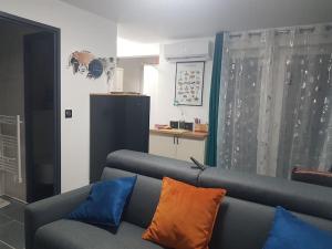 een woonkamer met een grijze bank met blauwe en oranje kussens bij APPT Cosy entier avec piscine in Toulouse
