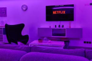 Una sala de estar morada con un sofá y un televisor. en Appartement Loft Cosy - 15mn de Paris !, en Fontenay-aux-Roses 4 fotos más