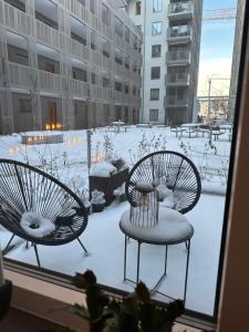 Dos sillas sentadas en una ventana con nieve. en Hagastaden flat en Estocolmo