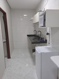 a white kitchen with a sink and a microwave at POUSADA FLAT MÃE RAINHA in Maceió