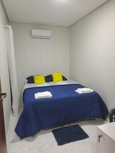 a bedroom with a blue bed with yellow pillows at POUSADA FLAT MÃE RAINHA in Maceió