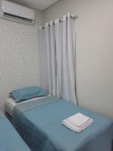 una camera da letto con un letto con lenzuola blu e una finestra di POUSADA FLAT MÃE RAINHA a Maceió