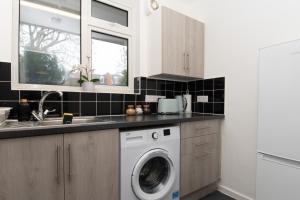 een keuken met een wasmachine en een wastafel bij Modern 1 bed flat on the outskirts of Kingston in Teddington