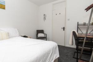 een slaapkamer met een bed, een bureau en een stoel bij Modern 1 bed flat on the outskirts of Kingston in Teddington