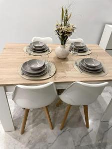 a wooden table with chairs and plates and a vase with flowers at Rincón Roma in Gelves