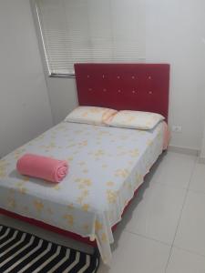 a bed with a red headboard and a pink pillow at VS HOSPEDAGEM in Cascavel