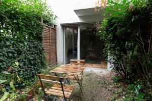 una mesa de picnic y dos bancos en un jardín en Appartement moderne, Metro 7, Parking et Jardin, en Villejuif