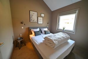 1 dormitorio con 1 cama con sábanas blancas y ventana en Bois de l'Ourthe 202, en Somme-Leuze
