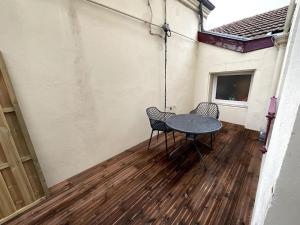 een patio met een tafel en stoelen op een houten vloer bij Émeraude - Centre-ville /Terrasse /Parking gratuit in Roanne