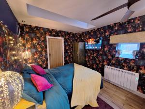 een slaapkamer met een blauw bed en een televisie bij Park House Studio in Matlock