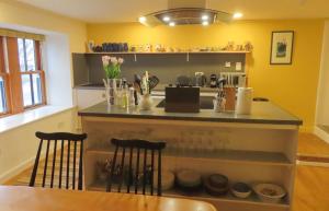 een keuken met gele muren en een aanrecht met stoelen bij West House in Stein