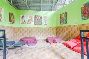 a room with two tables and paintings on the walls at Green View Ubud Hostel Bali in Ubud