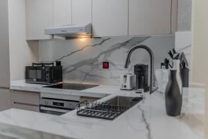a white kitchen with a sink and a counter top at Clever Guest Concorde JLT in Dubai