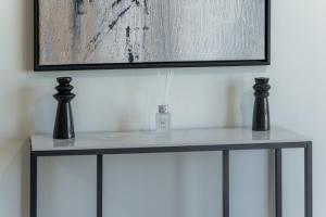 a table with two vases on it under a painting at Clever Guest Concorde JLT in Dubai