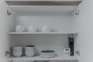 a white shelf with plates and bowls on it at Clever Guest Concorde JLT in Dubai