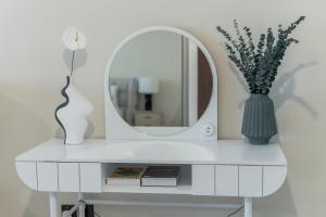 a white dressing table with a mirror and a vase at Clever Guest Concorde JLT in Dubai