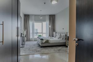 a white bedroom with a bed and a large window at Clever Guest Concorde JLT in Dubai