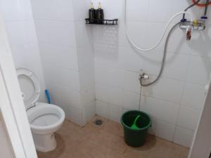 a bathroom with a toilet and a green bucket at Sansan Room - Apartemen Gunung Putri Square in Parungdengdek