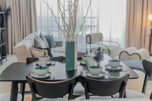a dining room table with chairs and a vase with branches at Clever Guest Concorde JLT in Dubai
