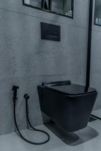 a black toilet with a hose attached to a wall at Clever Guest Concorde JLT in Dubai