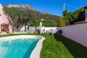 a swimming pool in a garden with a mountain in the background at ByNos Pool - Primo Piano in Santa Maria Navarrese