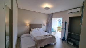 a bedroom with a bed with white sheets and a window at Casa PraiAmar Atalaia in Salinópolis