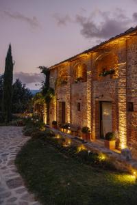 um grande edifício de tijolos com luzes à frente em Agriturismo Poggio Il Castellare em Montalcino