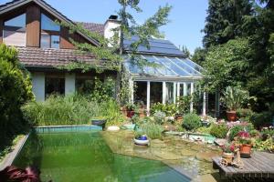 a house with a pond in front of it at Bed & Breakfast Wepfer in Grüt