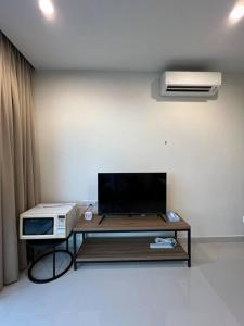 a living room with a tv and a table with a microwave at Kozi Square Dual Unit (1 bedroom, 1 living room) in Kuching