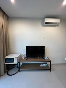 a living room with a tv and a table with a microwave at Kozi Square Dual Unit (1 bedroom, 1 living room) in Kuching