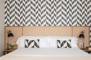 a bedroom with a white bed with black and white patterns at Hommyhome Vera-Cruz 1900 in Seville