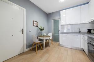 a kitchen with white cabinets and a table and chairs at 1 bedroom 1 bathroom furnished - Sol - Downtown - Minty Stay in Madrid